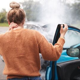Woman holding her painful neck after a car accident