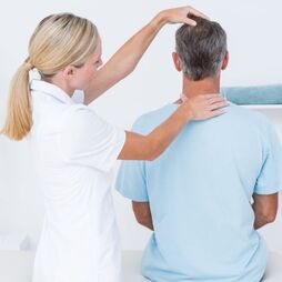 Chiropractor examining a patient's neck and upper back